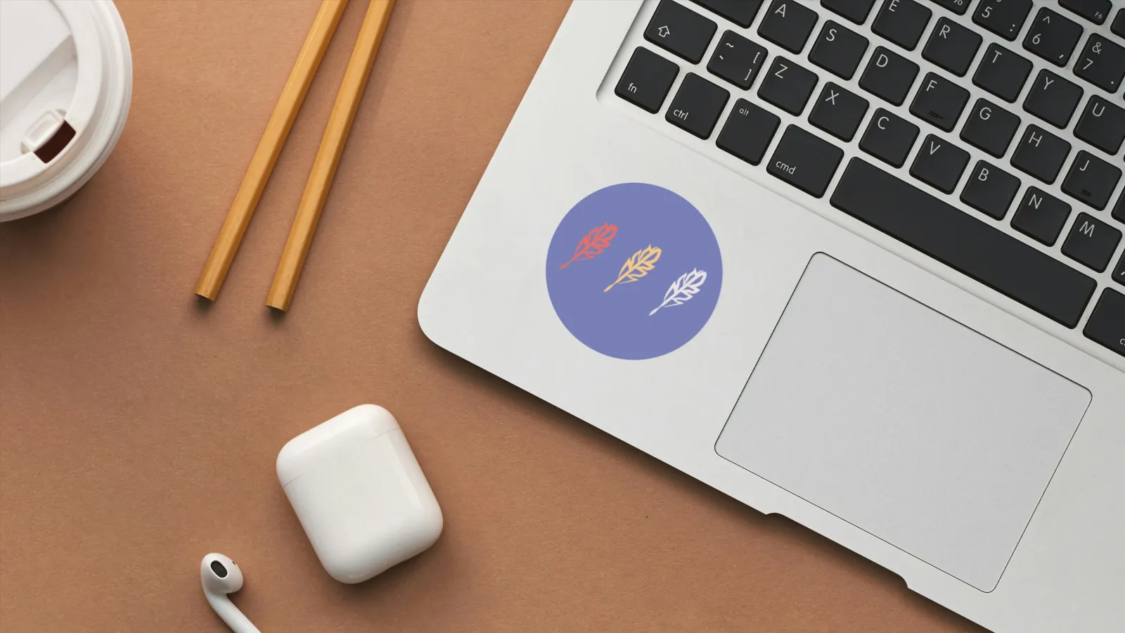 The image features a blue branded sticker with three of Chronical’s logo mark, a feather quill, on it. The sticker is pasted to a light grey laptop resting on a wooden desk holding air pods and office supplies.