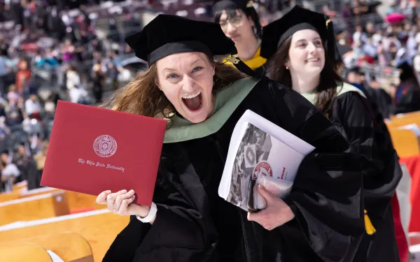 Happy graduates with diplomas. 2023 spring commencement in Ohio Stadium.