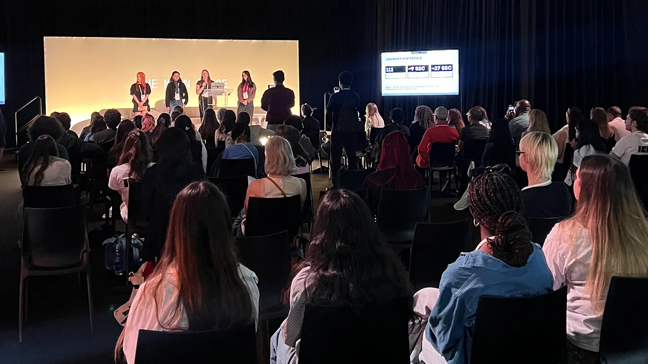 A student group presenting their work on stage in front of an audience. 